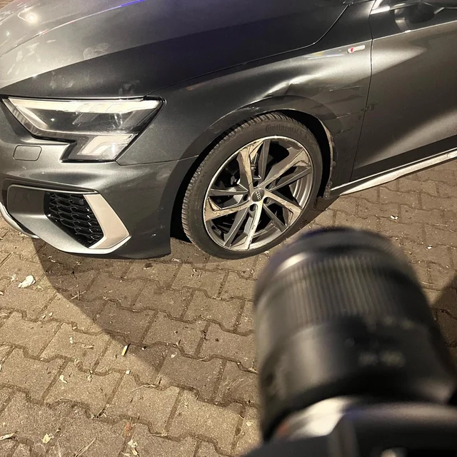 Fotodokumentation eines Schadens an einem schwarzen Fahrzeug